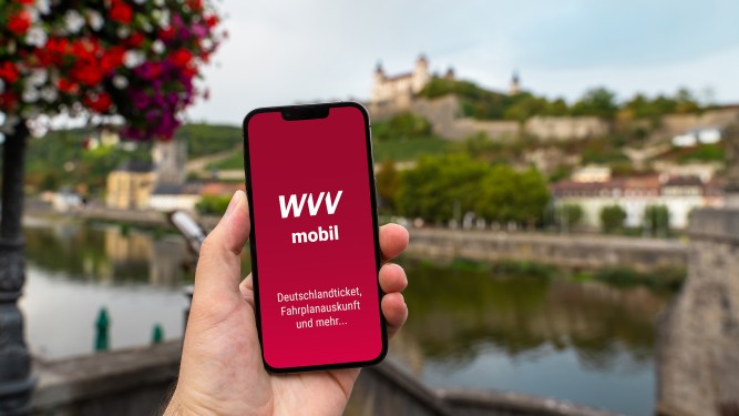 WVVmobil-App Hand, die Handy mit WVVmobil-App hält, im Hintergrund Festung von Würzburg